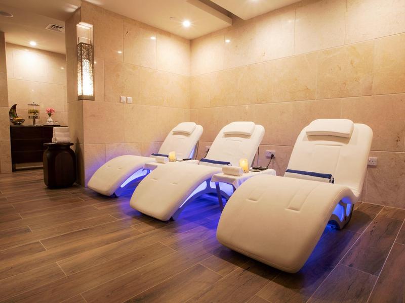 Moderne Entspannungsraum mit drei bequemen weißen Liegestühlen und warmem indirektem Licht.