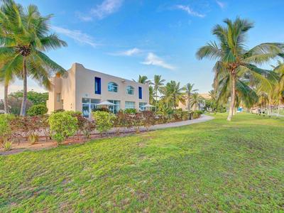 Edificio dell'hotel circondato da palme e prato verde sotto cielo sereno.