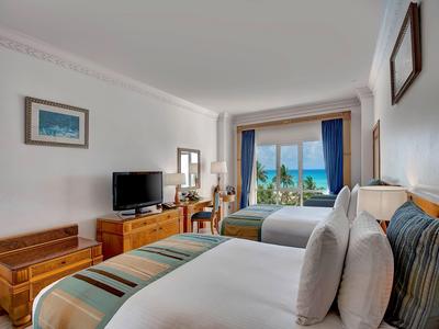 Camera d'hotel moderna con due letti e vista sul mare dalla finestra.