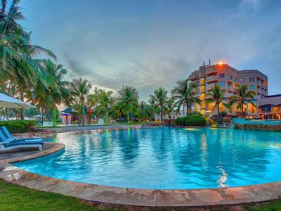 Velký venkovní bazén s lehátky a palmami při západu slunce