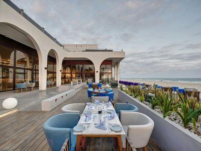 Terasa s jídelními stoly a židlemi s výhledem na moře v moderním hotelu.