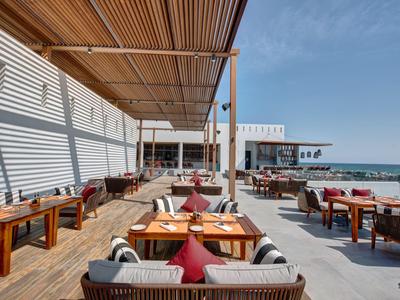 Otevřená plážová restaurace s dřevěnou terasou a posezením s výhledem na moře.