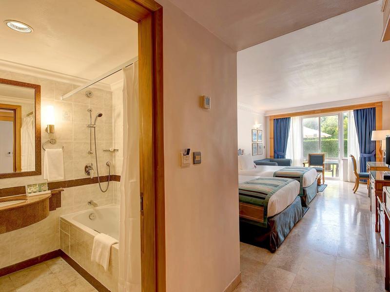 Vista di una camera d'hotel con letto matrimoniale e bagno adiacente con doccia.