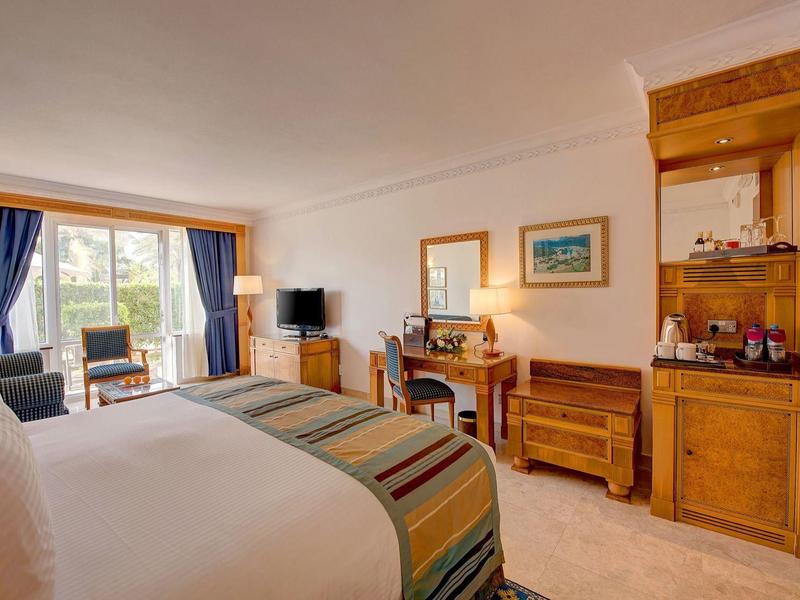 Camera d'albergo luminosa con letto grande, scrivania, TV e balcone con vista esterna.