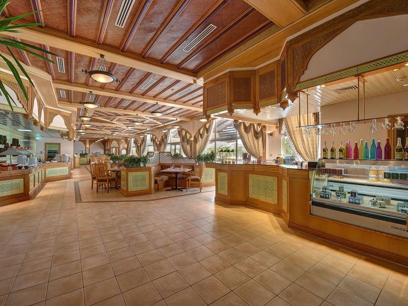 Ampia hall d'hotel aperta con travi di legno, aree salotto e bancone.