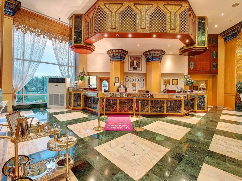 Elegante bar dell'hotel con pavimento in marmo, accenti in legno e grande finestra con vista esterna.