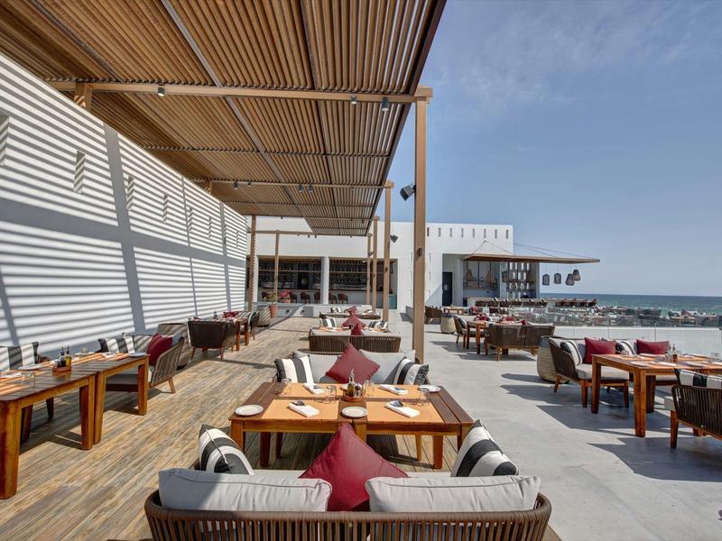 Terrazza soleggiata con mobili in legno con vista sulla spiaggia e sul mare.