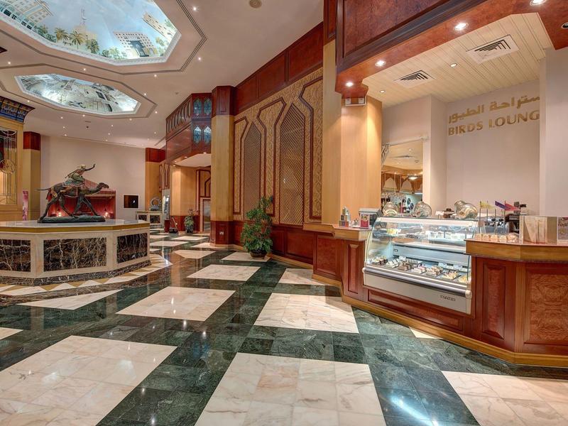 Elegante hall dell'hotel con pavimento in marmo, bancone chiaro e finestre decorative sul soffitto.