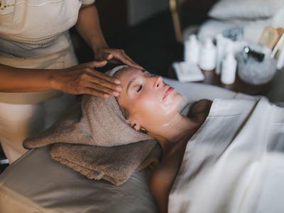 Femme recevant un massage de la tête avec une serviette sur la tête dans un spa.