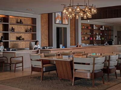 Espace lounge d'hôtel élégant avec fauteuils modernes et étagères éclairées.