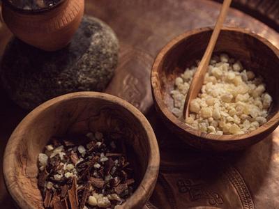 Trois bols en bois sur un plateau avec des herbes, des épices et un bol fumant.