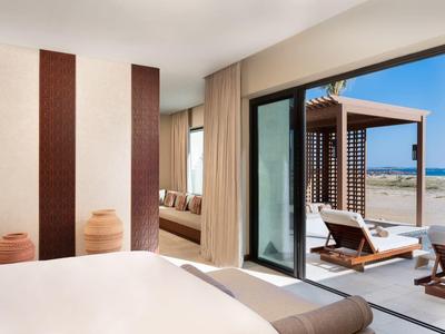 Chambre d'hôtel moderne avec lit blanc, terrasse et vue sur la mer.