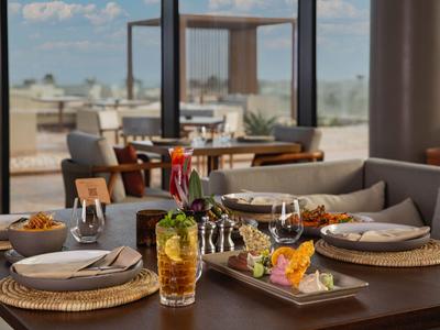Eleganter Tisch mit Snacks und Getränken in einem modernen Hotelrestaurant mit Blick nach draußen.