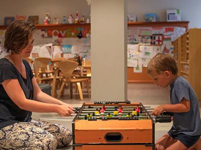 Une femme et un garçon jouent au baby-foot dans une salle de jeux conviviale pour enfants.
