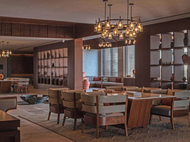 Salle à manger d'hôtel moderne avec meubles en bois et lustres élégants.