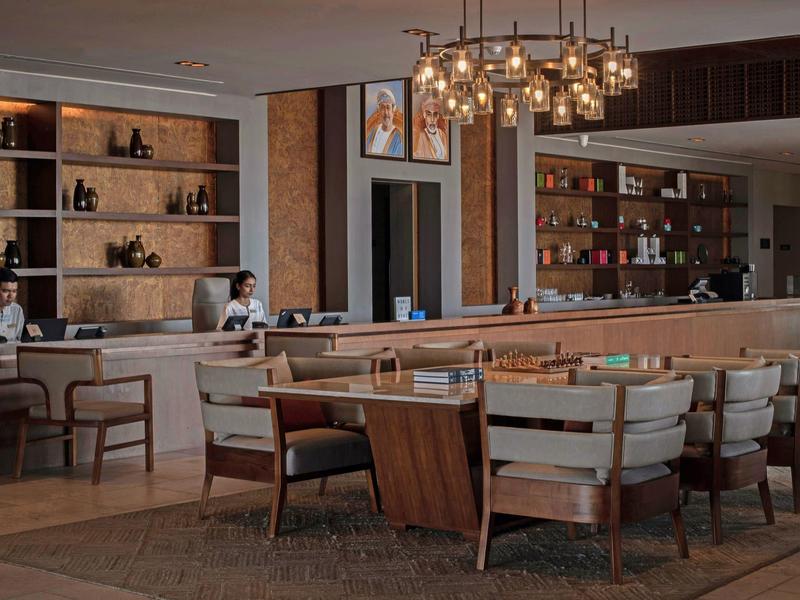 Espace lounge d'hôtel élégant avec fauteuils modernes et étagères éclairées.