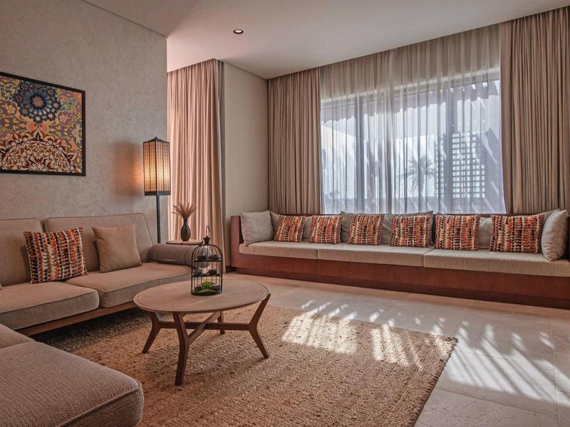 Salon lumineux avec grandes fenêtres, canapés confortables et décoration moderne.