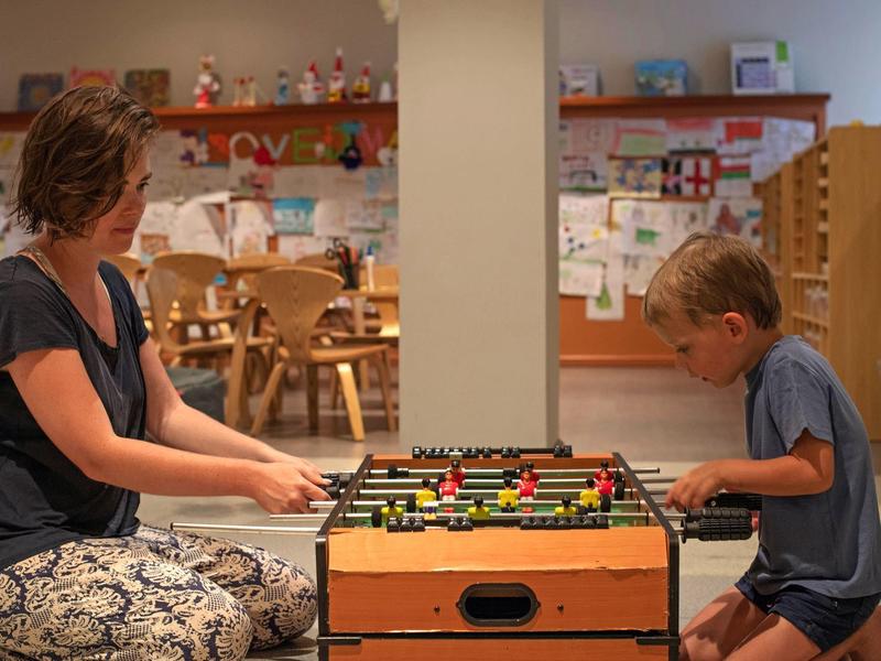 Une femme et un garçon jouent au baby-foot dans une salle de jeux conviviale pour enfants.
