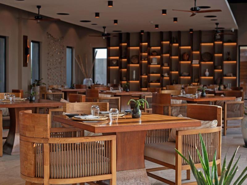 Restaurant moderne avec chaises en bois et éclairage chaud sur le mur arrière.