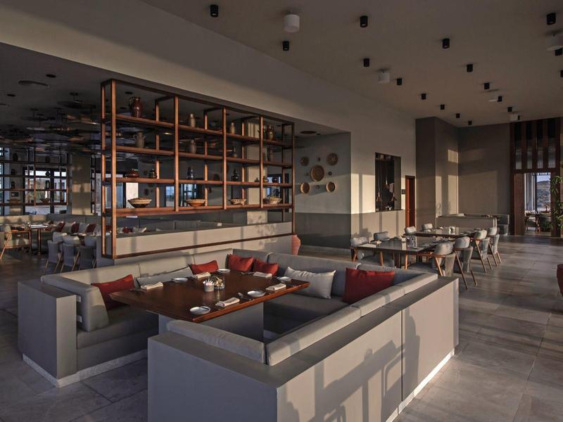 Espace lounge d'hôtel moderne avec canapés, tables et éclairage élégant.