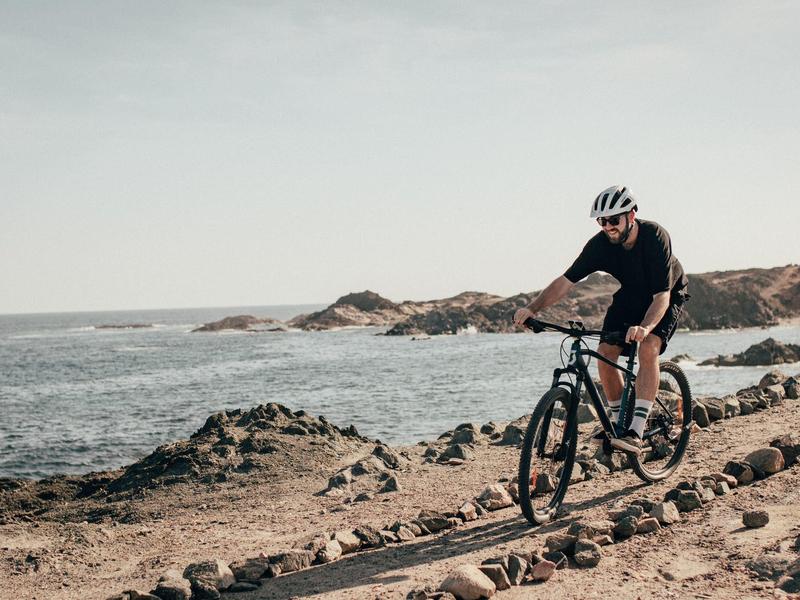 Homme faisant du vélo sur un chemin rocheux au bord de la mer.