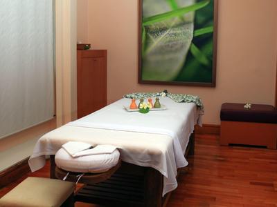 Gezellige behandelruimte met massagetafel, houten vloer en rustgevende wanddecoratie.