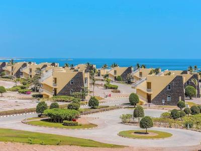 Rijen schuine gebouwen in een resort met uitzicht op zee onder een heldere blauwe lucht.