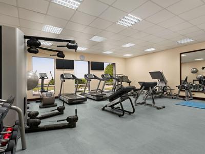 Helles Fitnessstudio mit modernen Geräten und großen Fenstern