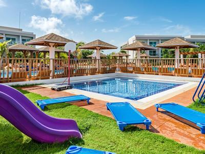 Ein kleiner Pool mit blauer Rutsche, blauen Liegestühlen und Holzgeländer in sonniger Gartenanlage.