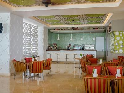 Moderner Lounge-Bereich mit grüner Decke, roten Sesseln, weißen Stühlen und poliertem Boden.