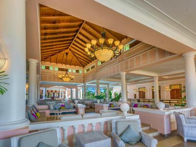 Großer, offener Lobbybereich mit hohen Säulen, Holzdecke und elegantem Kronleuchter.