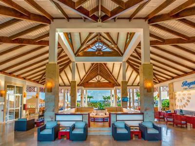 Offene Hotellobby mit Holzbalkendecke, Sitzbereichen und Blick auf Außenbereich mit Becken.