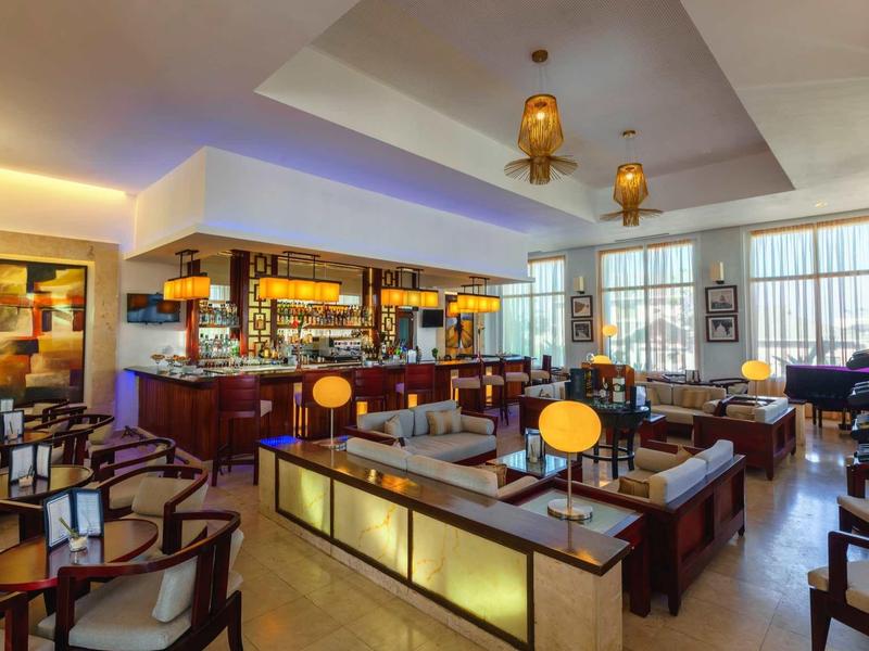 Modernes Restaurant mit warmem Licht, Holzstühlen, Tischen und großen Fenstern für Tageslicht.