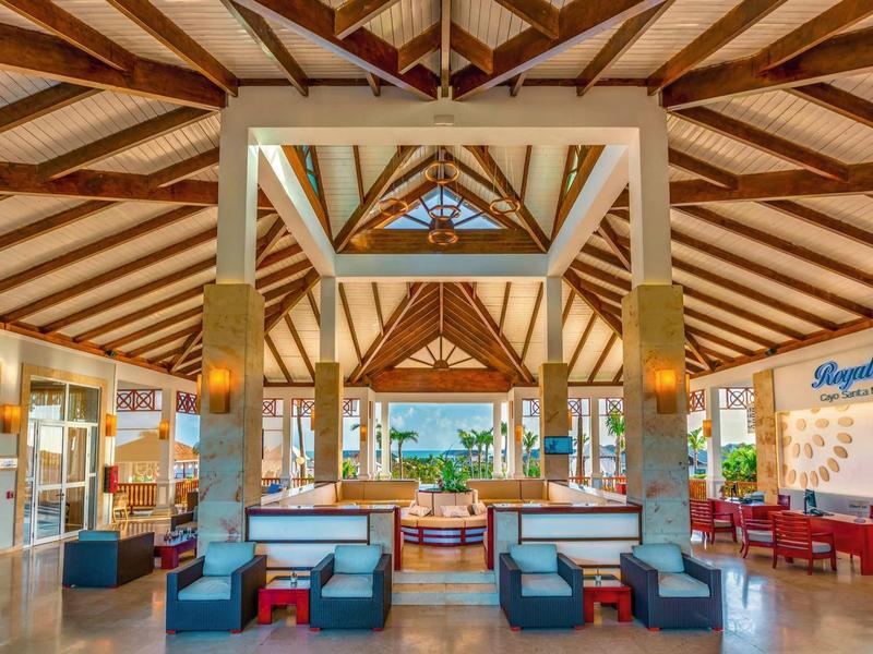 Helle, offene Hotel-Lobby mit Holzdecken, Säulen und modernen Sitzbereichen in warmen Farben.