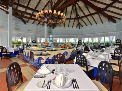 Elegantes, helles Restaurant mit hohen Decken und stilvoll gedeckten Tischen.