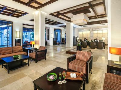 Moderner Lobbybereich mit bequemen Sesseln, Sofas, Tischen und warmem Licht in hellem Marmorboden.