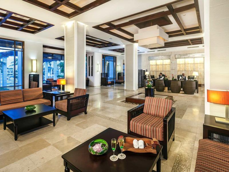 Moderner Lobbybereich mit bequemen Sesseln, Sofas, Tischen und warmem Licht in hellem Marmorboden.