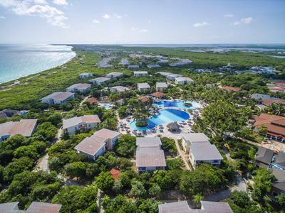 Luftaufnahme eines Resorts mit Pool, umgeben von grüner Vegetation und nahe am Meer.