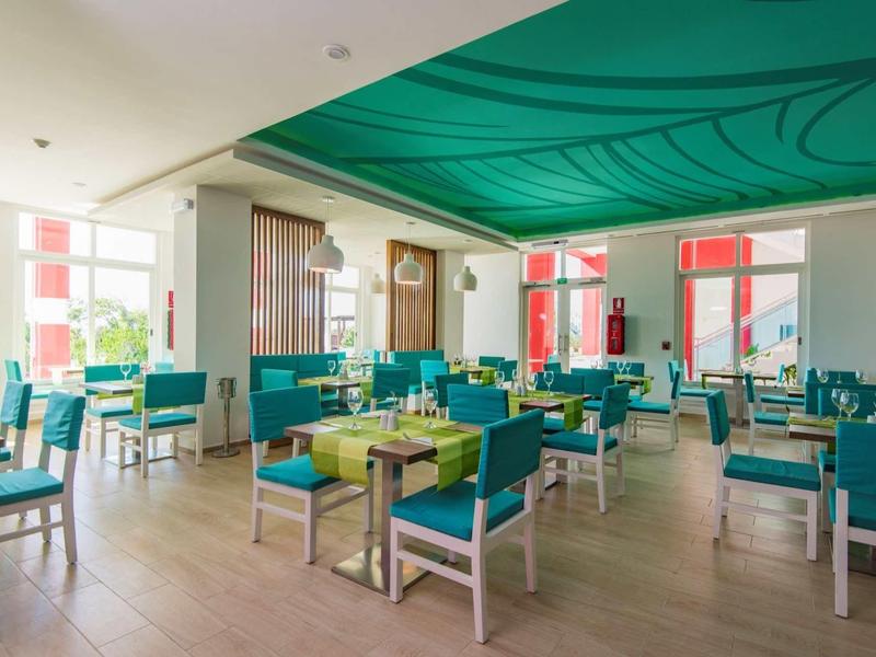 Helles Restaurant mit grünen Stühlen, weißen Tischen und grünem Stoffdach, modernes Design.