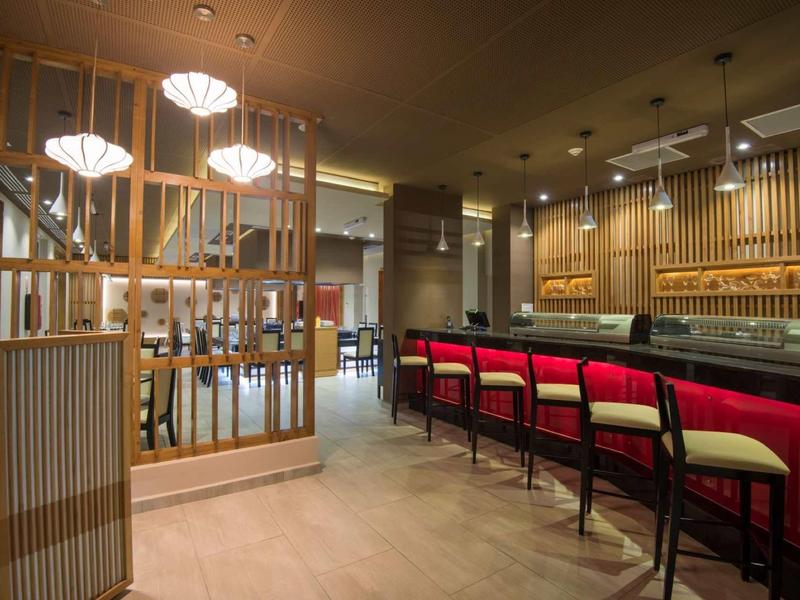 Moderner Barbereich mit Holzverkleidung, roten Barhockern und elegantem Deckenlicht.