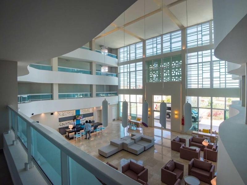 Helle Lobby mit hohen Fenstern, moderner Sitzmöbelgruppe und offenem Galerie-Design.