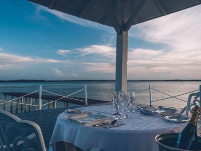 Ein gedeckter Tisch mit Gläsern und Wein auf einer Terrasse mit Blick auf das Meer bei Sonnenuntergang.