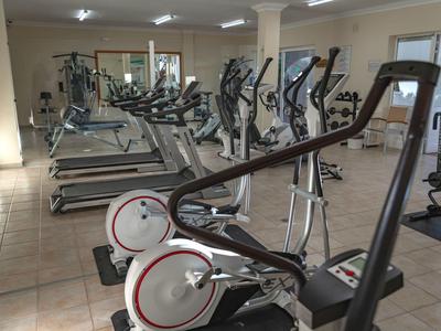 Fitnessraum mit verschiedenen Trainingsgeräten und großen Spiegeln an den Wänden.
