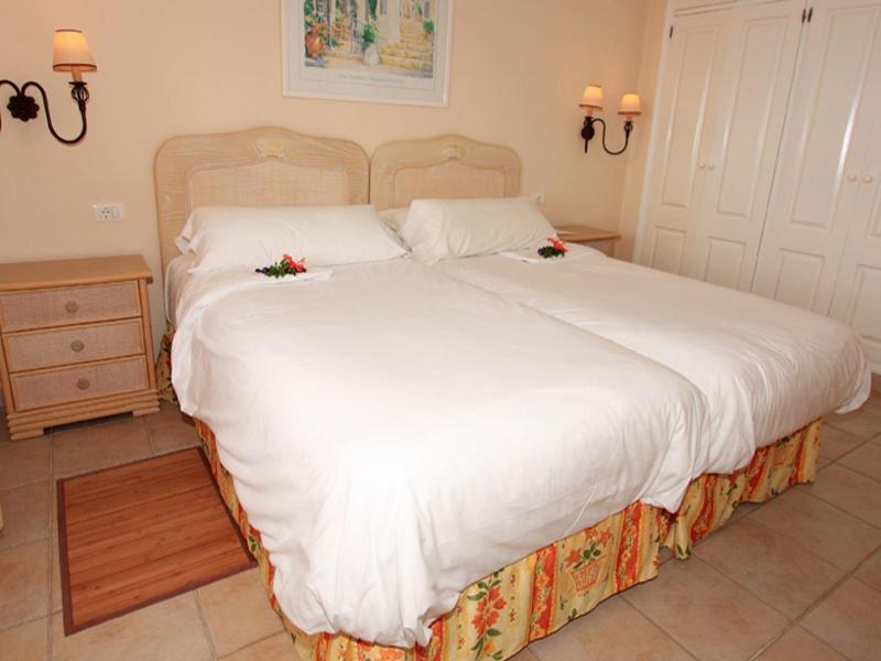 Brightly furnished bedroom with two single beds, nightstands, and curtains.