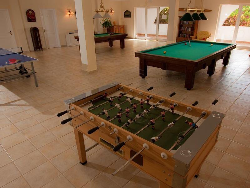 Large game room with foosball, billiards table, and ping pong table in a bright space.