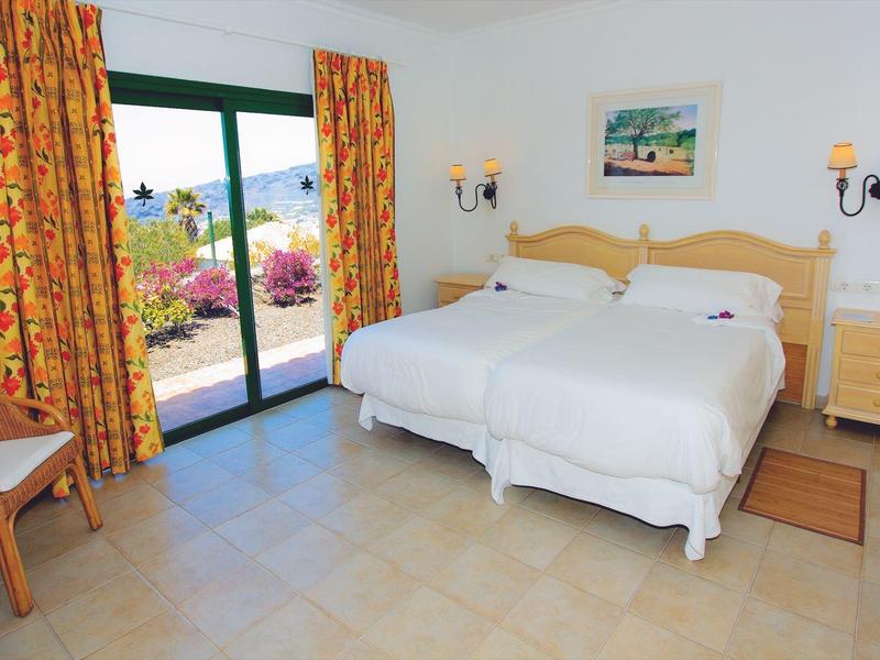 Brightly decorated bedroom with two single beds and access to a terrace