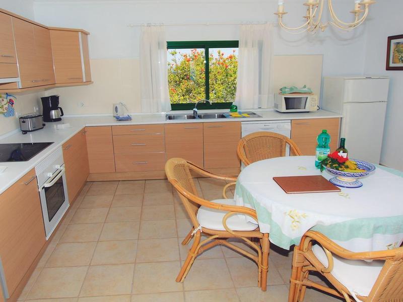Bright kitchen with wooden cabinets, dining table, and rattan chairs by a window with a view
