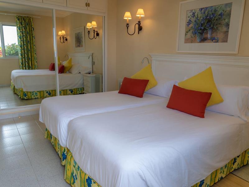 Bright hotel room with two beds, soft pillows, and a large wall mirror.