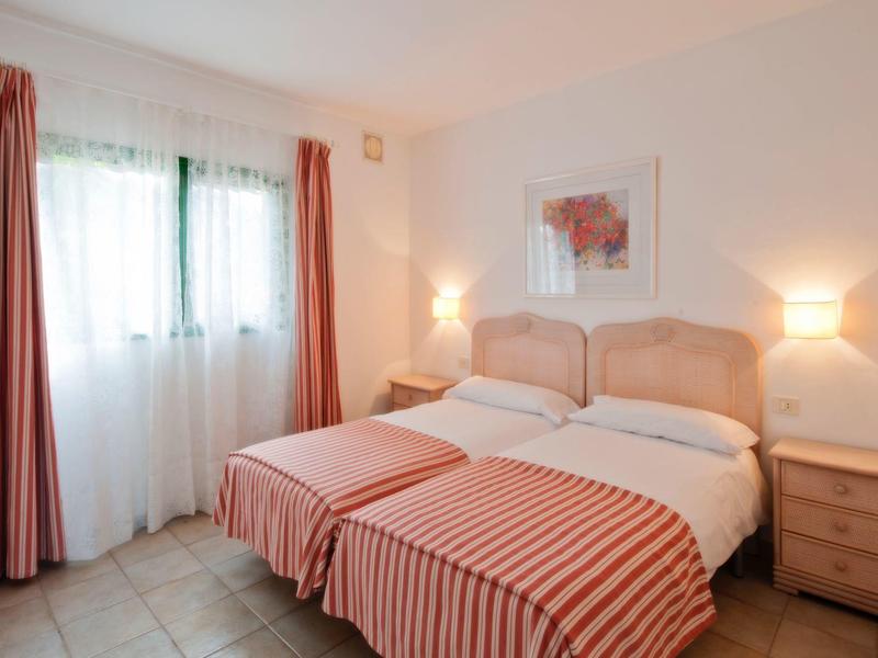 Cozy hotel room with two beds, red curtains, and nightstands with lamps.