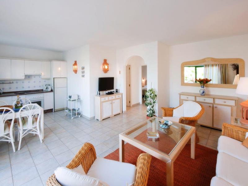 Bright living space with white kitchen, dining area, and cozy seating with sofas.